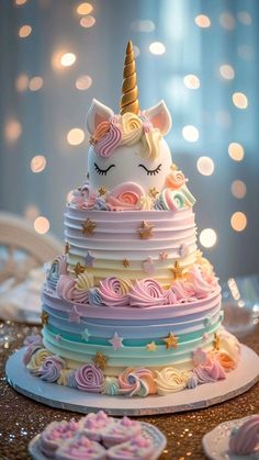 a multi layer cake with a unicorn face on top, surrounded by cookies and icing