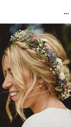 a woman with flowers in her hair smiling at the camera while wearing a flower crown