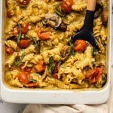 a white casserole dish filled with pasta and vegetables