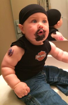 a baby sitting on top of a sink with a fake mustache in it's mouth