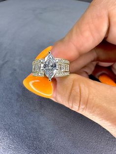 a woman's hand holding an orange and white ring on top of her finger