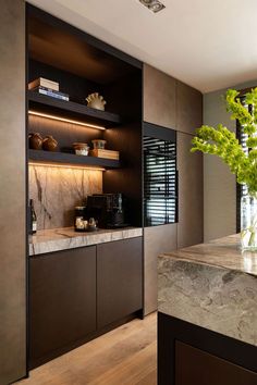 a kitchen with marble counter tops and wooden shelves, along with a vase filled with flowers