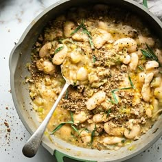 a large pot filled with food on top of a white countertop next to a wooden spoon