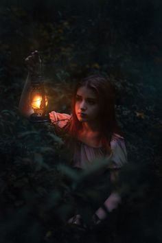 a girl holding a lantern in the woods