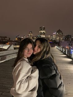 two women standing next to each other on a bridge