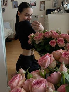 a woman taking a selfie with flowers in front of her and on the phone