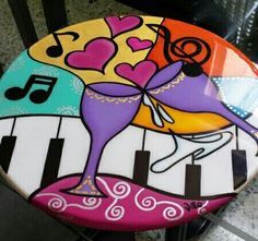 a painted stool with musical notes and a dog on it's back, next to a piano