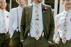 a group of men standing next to each other wearing ties and suspenders with flowers on them