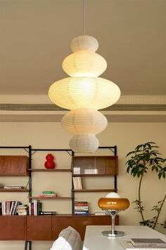 a living room filled with furniture and a lamp hanging over it's head in front of a bookshelf