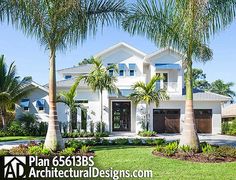 a large white house with palm trees in the front yard