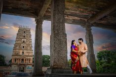 a man and woman standing in front of an old building with columns on each side