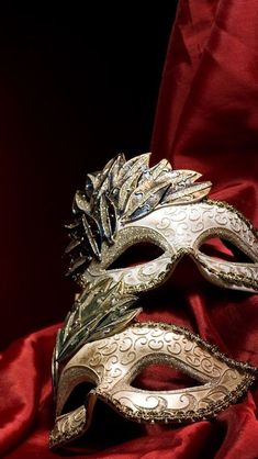 two masquerade masks sitting on top of a red cloth