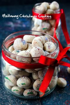 two glass jars filled with white chocolate covered cookies and red ribbon tied around the top