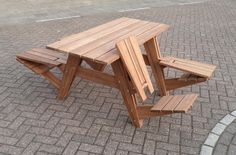 a wooden picnic table sitting on top of a brick sidewalk