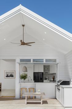 an outdoor living area with white walls and ceiling fan