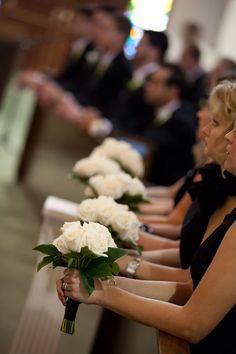 a row of white roses sitting next to each other on top of pews in a church