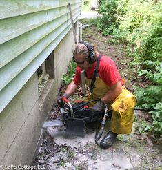 a man in yellow overalls and headphones using a chainsaw