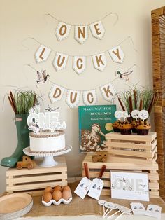 there is a cake and other items on the table in front of the sign that says one lucky ducky