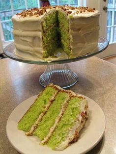 a green cake sitting on top of a table next to a slice cut out of it