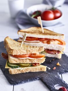 two sandwiches cut in half sitting on top of a black slate board with tooth picks