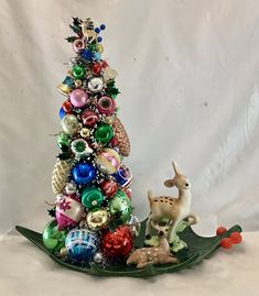 an ornament christmas tree with ornaments on it and a deer figurine next to it