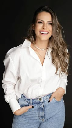 a woman with long hair wearing jeans and a white shirt is smiling at the camera