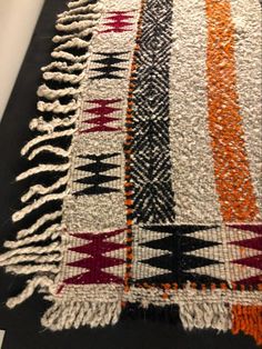 a black and white rug with orange, red, and grey designs on it's sides