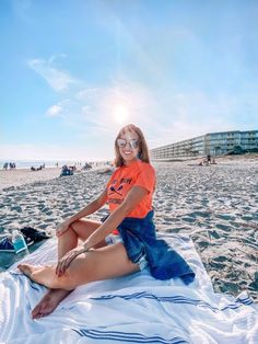 a woman sitting on top of a towel at the beach