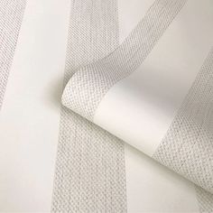 a white and grey wallpaper with vertical stripes on it's side, next to a roll of paper