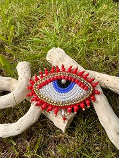 a piece of drift wood with an eye bead on it sitting in the grass