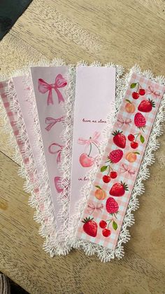 four paper bookmarks with strawberries and cherries on them sitting on a table