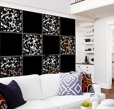 a living room filled with white furniture and lots of black tiles on the wall behind it