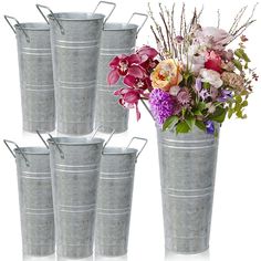 four metal buckets with flowers in them on a white background and one is empty