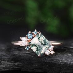 a green and white stone ring on top of a piece of wood with leaves in the background