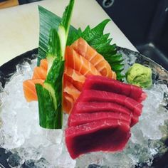 a plate that has some kind of sushi on top of ice with other food items around it