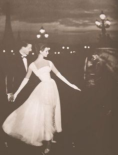 a man and woman in formal wear are walking through the street at night with their arms around each other