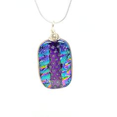 The item listed is a fused glass necklace that was handcrafted in my studio in Washington, NJ.This necklace was created by using a combination of dichroic and plain glass. The glass was cut and then layered and pieced together before being heated in a kiln to fully fuse the glass. It was then shaped on a grinder and put in the kiln again to be fire polished in order to give it a final shine. After that, a channel was grooved into the side so that it could be wire-wrapped.Some of the glass in thi Unique Iridescent Glass Necklaces, Fused Glass Necklace, Dichroic Glass, Glass Necklace, Necklace Silver, Fused Glass, Kiln, Silver Necklaces, Wire Wrapped