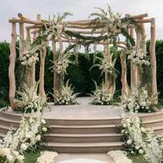 an outdoor wedding setup with white flowers and greenery on the steps leading up to it