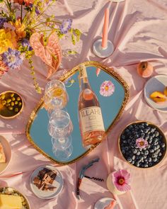 a table topped with plates and bowls filled with food next to a bottle of wine