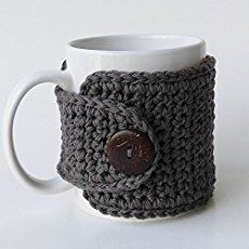 a crocheted coffee cup holder with a button on the front and bottom, sitting on a white surface