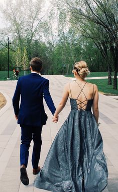 a man and woman in formal wear walking down the street holding hands with each other