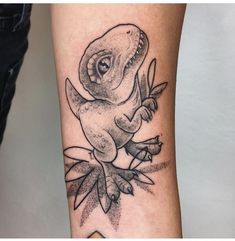 a black and white tattoo of a dinosaur on the arm with leaves around it's neck