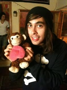 a young man holding a stuffed monkey in his right hand and smiling at the camera