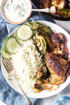 two plates filled with meat, rice and cucumbers