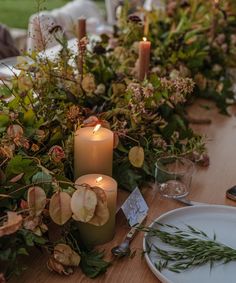 the table is set with candles and greenery for an outdoor dinner party or gathering