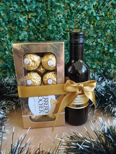 a bottle of wine and some chocolates in a box with a bow around it