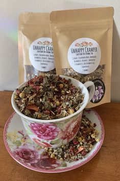 two bags of tea sitting on top of a table next to a cup and saucer