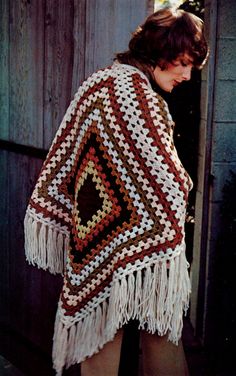 a woman wearing a crocheted shawl with fringes