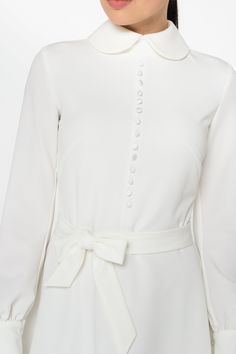 "A collared midi dress featuring a button front closure (imitation), fabric belt, and a fit and flare silhouette. - fit and flare silhouette - high rounded collar - knee length (midi) - long sleeves with cuffs - fabric belt - covered button front decor - concealed zipper closure - lined bodice and skirt - color: white Fiber: 60% viscose, 35% polyester, 5 % elastane, Lining - 95 % viscose, 5% elastane. For size S:dress length- 40,0 \" (102 cm), sleeve length 24,21\" (61,5 cm) Our model wears size Elegant Long Sleeve Wedding Mini Dress, Elegant Long Sleeve Maxi Dress With Button Closure, Classic A-line Midi Dress For Wedding, Elegant A-line Dress With Covered Buttons, Elegant Belted Midi Dress With Button Closure, A-line Midi Dress With Covered Buttons, Classic A-line Maxi Dress For Wedding, Chic A-line Long Sleeve Wedding Dress, Cream Long Sleeve Maxi Dress For Wedding