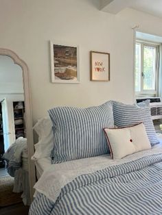 a bed with blue and white striped comforter next to a window in a bedroom